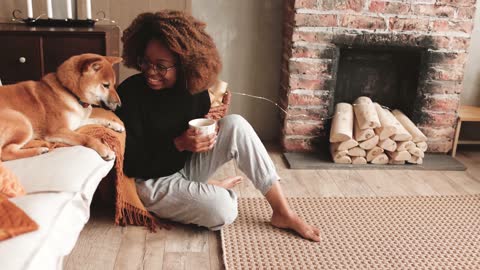 Woman Holding A Cup While Play With A Dog