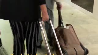 An older man dragging brown suit case