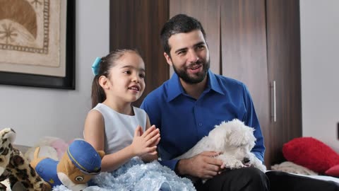 Father and daughter both of watching tv with their little dog.