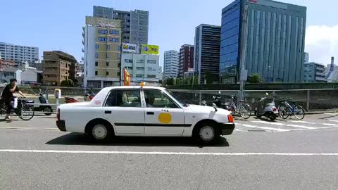 Small Japanese cars pass by.
