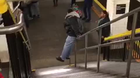 Man slides down staircase handrail in subway station