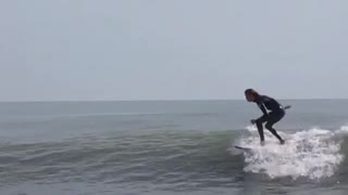White board black suit surfer falls off