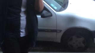 Drunk guy in blue flannel slips off of car on sidewalk