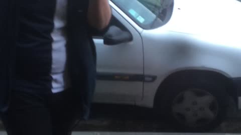 Drunk guy in blue flannel slips off of car on sidewalk