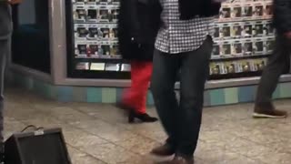 Man dances to band playing music in subway station