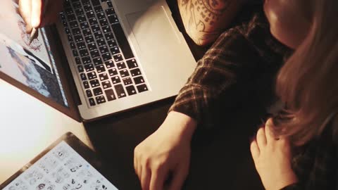 Man Tracing Tattoo Design from Laptop Screen