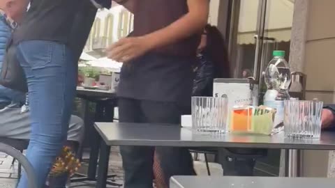 African immigrant puts her hands around neck of an Italian waitress who was simply doing her job