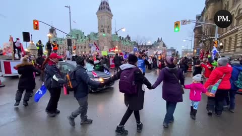 Supporters of the Freedom Convoy hold hands and sing “We Are the World”