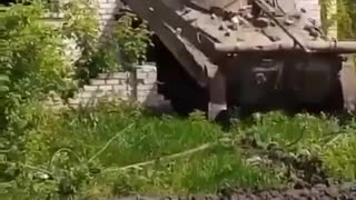 Ukrainian tank exits from hiding spot inside brick dwelling, June 2023