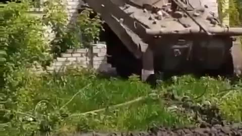 Ukrainian tank exits from hiding spot inside brick dwelling, June 2023