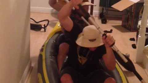 Two guys in inflatable boat pretend to paddle in house