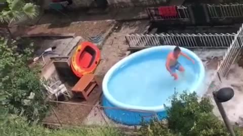Guy records friend jumping into blue blow up pool in backyard home breaks pool water spills