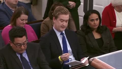 Watch the expression on the face of the lady in pink seated behind Peter Doocy .