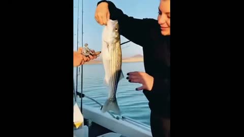 Woman holds fish she caught and tries to kiss it