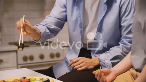 Japanese Man Picking A Piece Of Sushi With Chopsticks And Giving It To His Friend To Taste
