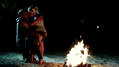 Couple embracing outdoors near a campfire at night