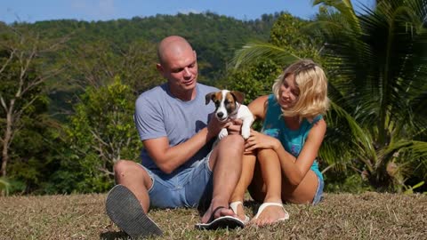 Happy Couple Holding a Puppy Dog Outdoors