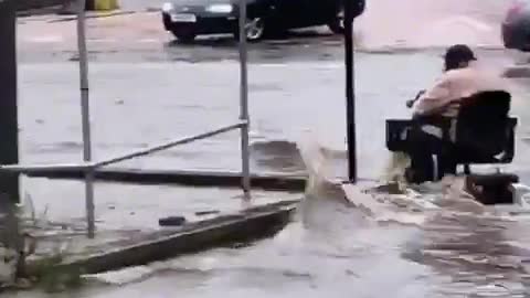 Fearless person on a motorized scooter during a flood