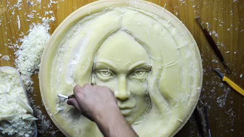 Artist sculpts face from wheel of cheese