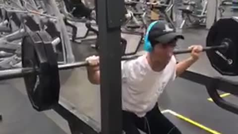 A guy blue head phones falls doing squats