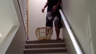 Guy slides down his stairs in a laundry basket and falls down stairs