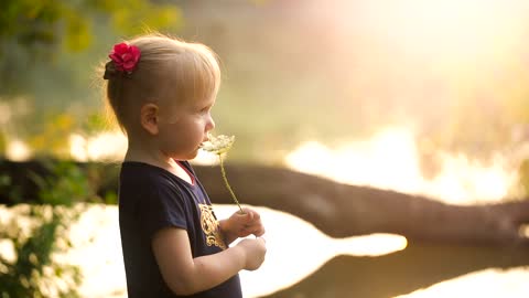 Young little girl smelling a blossom in nature