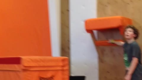 Kid jumping on orange gymnasium back flip