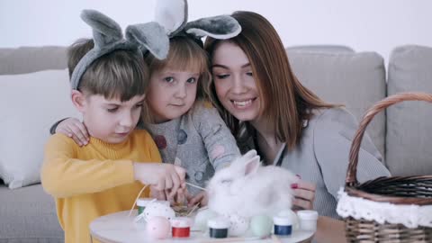 A Boy With Her Mom And Sister Trying To Feed A Rabbit With Grass Hay