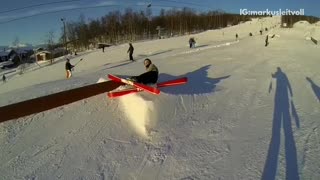 Green jacket skiier tries to grind rail and falls down