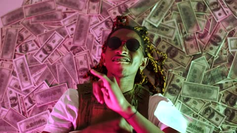 Rapper lying in a pile of money throwing money in the air