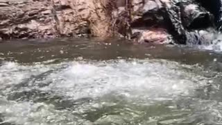 Slo-mo video guy slides down small waterfall