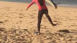 Teen in red wetsuit blue snorkeling shoes runs on beach