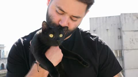 Close up of bearded hipster guy holding a big beautiful black cat