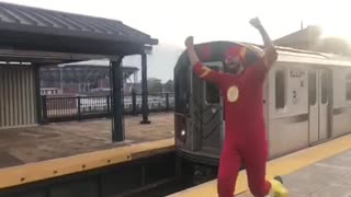 Man in red flash costume running next to subway train