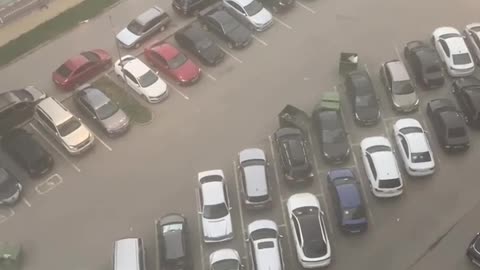 Wind pushes several trash cans along a parking site