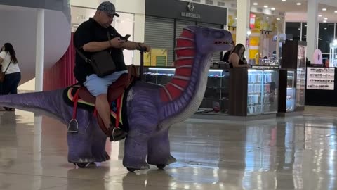 Man Rides Dinosaur Through Shopping Center