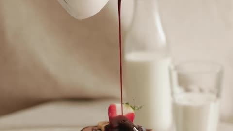 A Person Pouring Chocolate Syrup on Pancakes