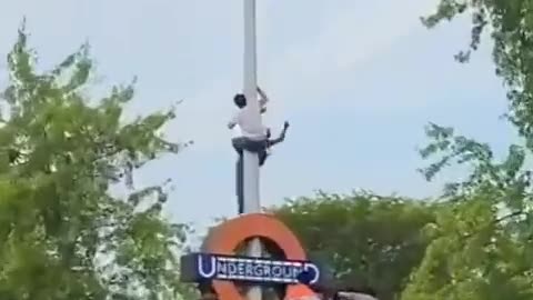 UK - Pajeet trying to tie an Indian flag to the underground sign falls down like a sack of shit