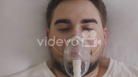 Sick Man Lying On Bed Breathing Through Oxygen Mask 1