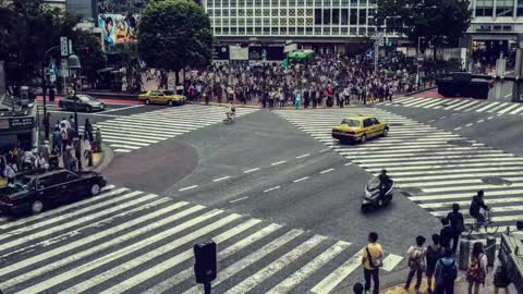 Crowds of people cross a street junction