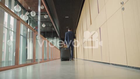 An Unrecognizable Businessman Walks Backwards With A Trolley 3