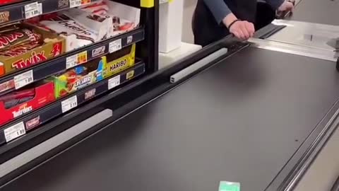 Cashier is waiting on tic tacs to go all the way down the conveyor belt