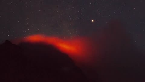 Active volcano smoking during the starry night