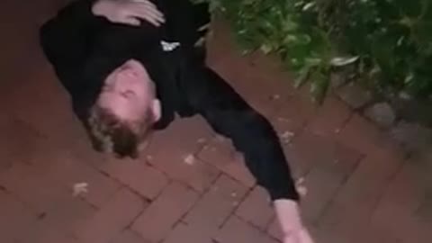 Guy in black sweater outside in the dark dives into bush