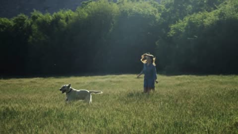 girl running in field towards dog