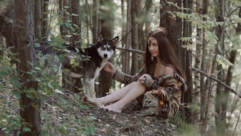 Attractive young woman sitting in the wild with beautiful dog