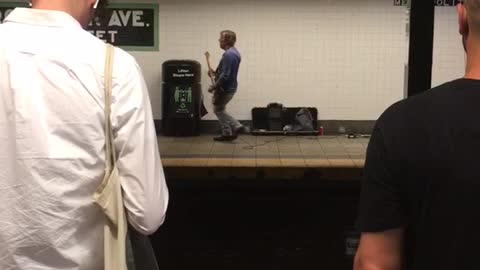 Man playing guitar on other side of tracks