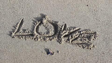 Writing the word LOVE on sand