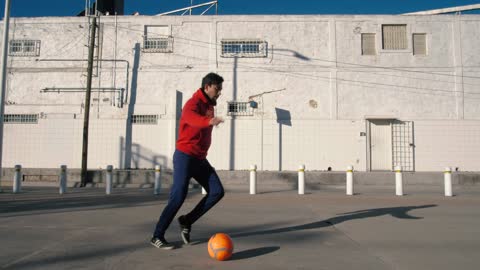 Young man playing soccer in the street