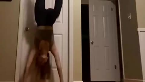 chick tries a hand stand against door and she falls flat on her back.